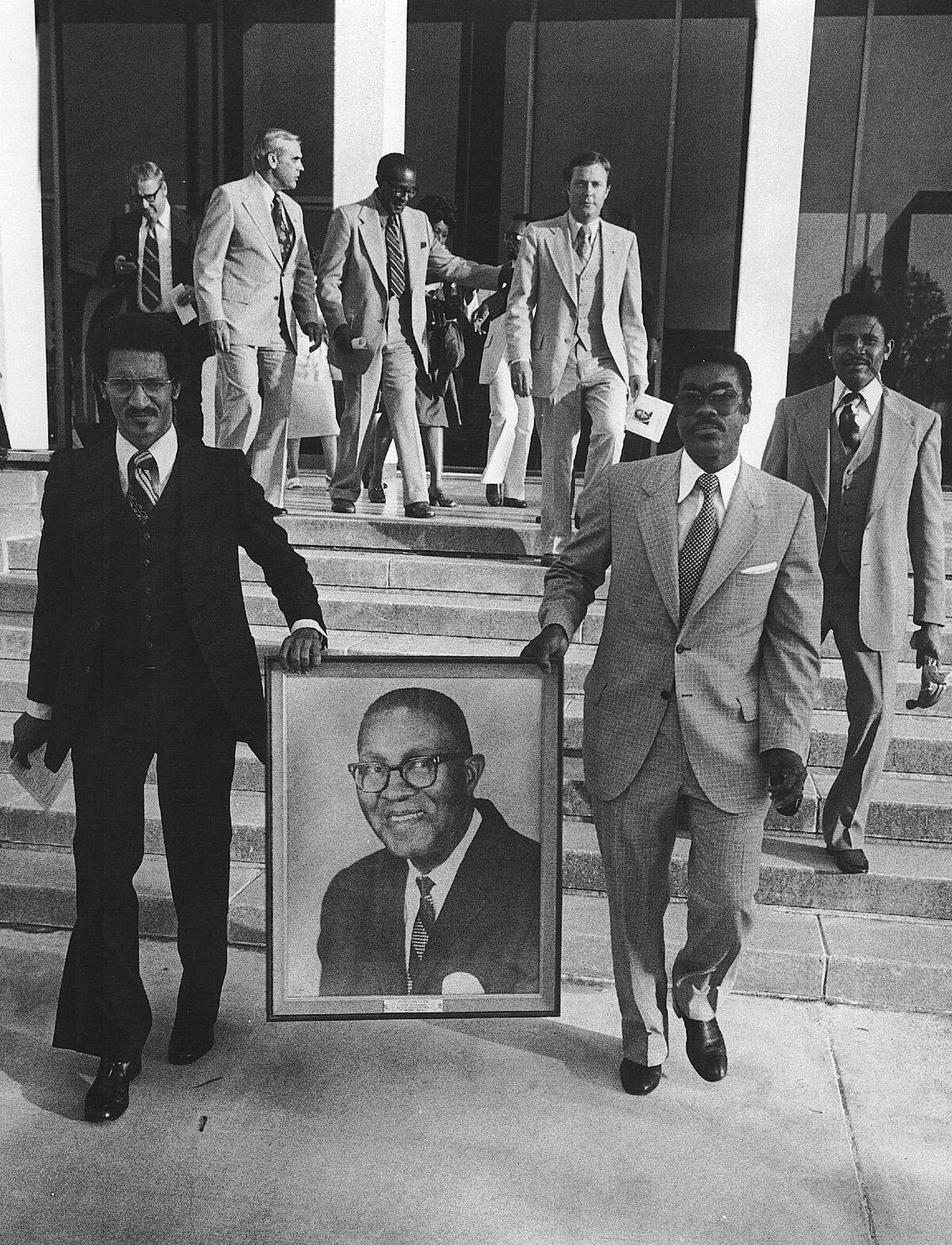 John Allen, left, today a semi-retired Superior Court judge, was in the 1940s an attorney and chairman of the civil rights group the Rainbow-PUSH Coalition. Allen and the Rev. William Howell, right, also with Rainbow-PUSH, carried a portrait of Primus King as they led a procession into the Government Center, with King and his wife Genie right behind them.