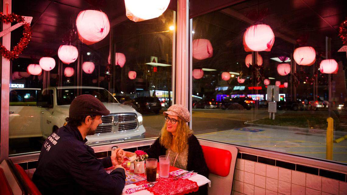 Valerie Deschamps-Goren, right, holds hands with Basil Gravanis while dining at a Waffle House restaurant decorated for Valentine’s Day in Atlanta, Wednesday, Feb. 14, 2018.