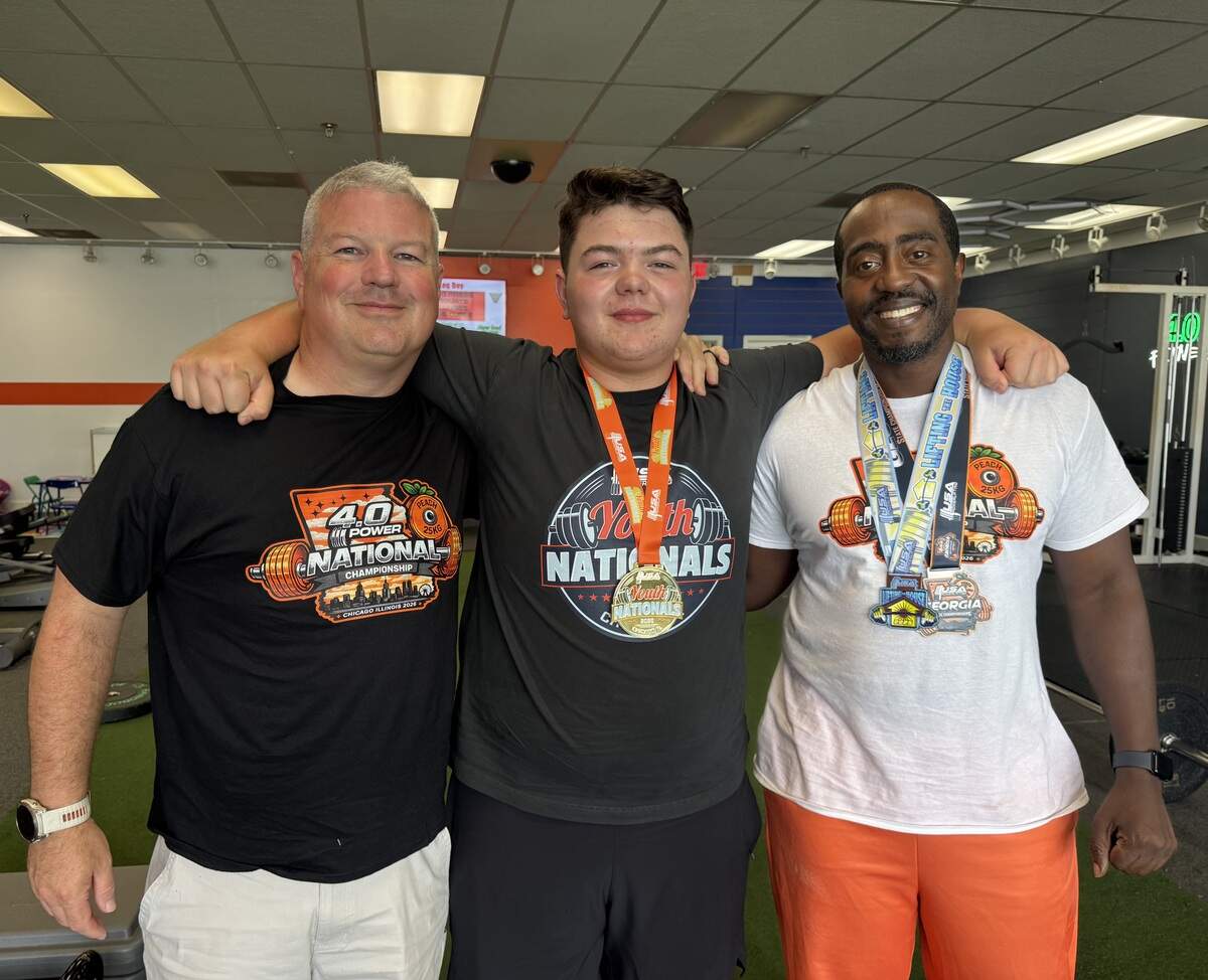 Nash Earwood poses with his father, Ryan Earwood, and coach Terrence Flowers at 4.0 Fitness in Columbus.
