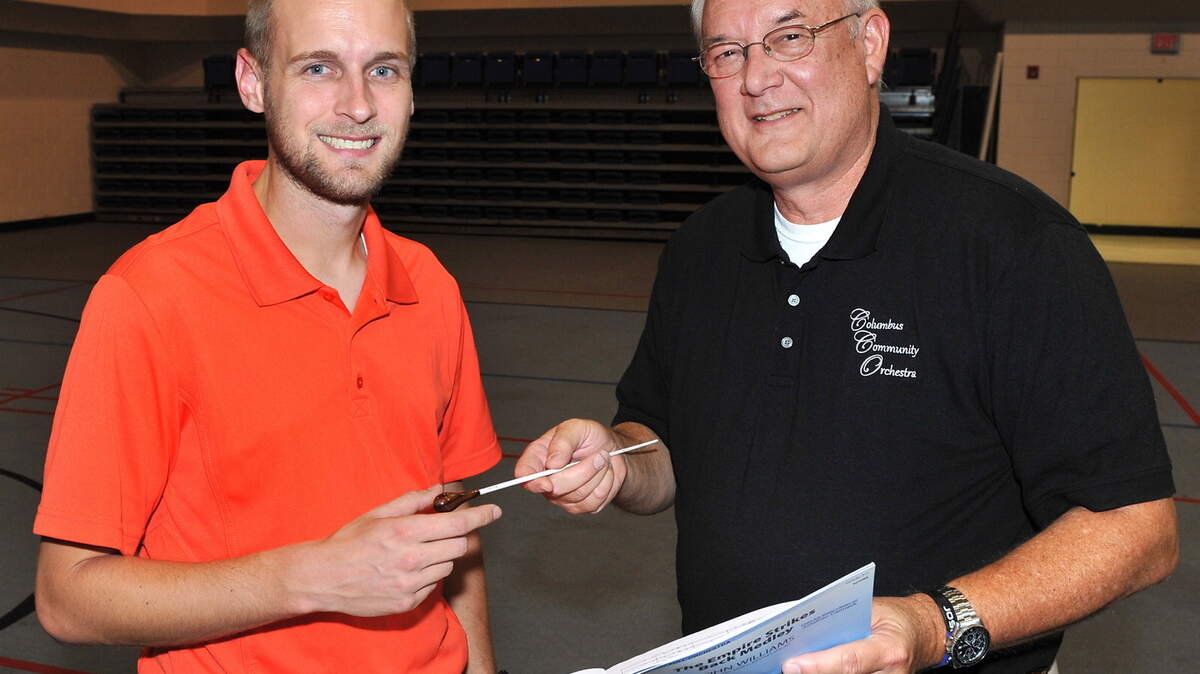 Special to the Ledger-Enquirer/Darrell Roaden; 
 Jon Carmack, left, receives the conductor's baton from William Fry during a Columbus Community Orchestra rehearsal last month in the St. Mark United Methodist Church Activity Center. 09/28/15
