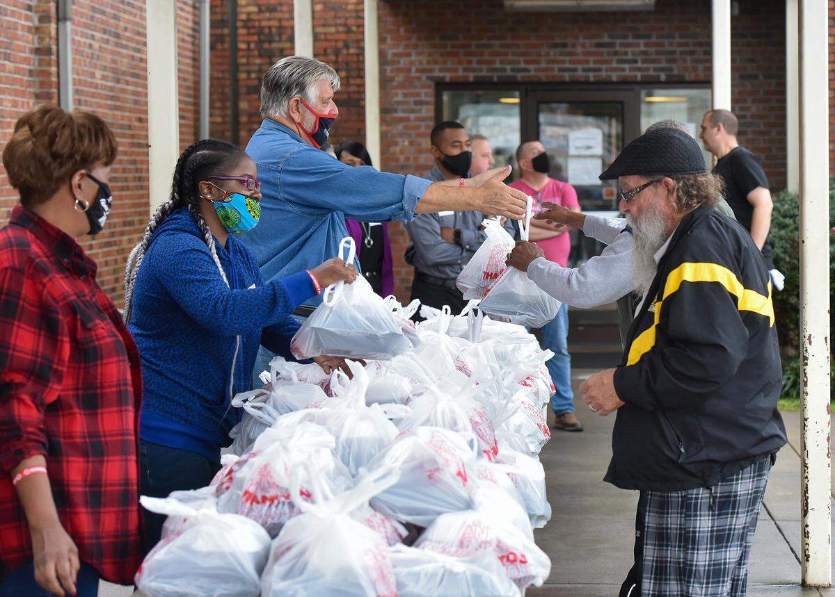 Valley Rescue Mission volunteers greet guests with serving trays filled with turkey and other Thanksgiving dishes on Thursday, November 26, 2020.