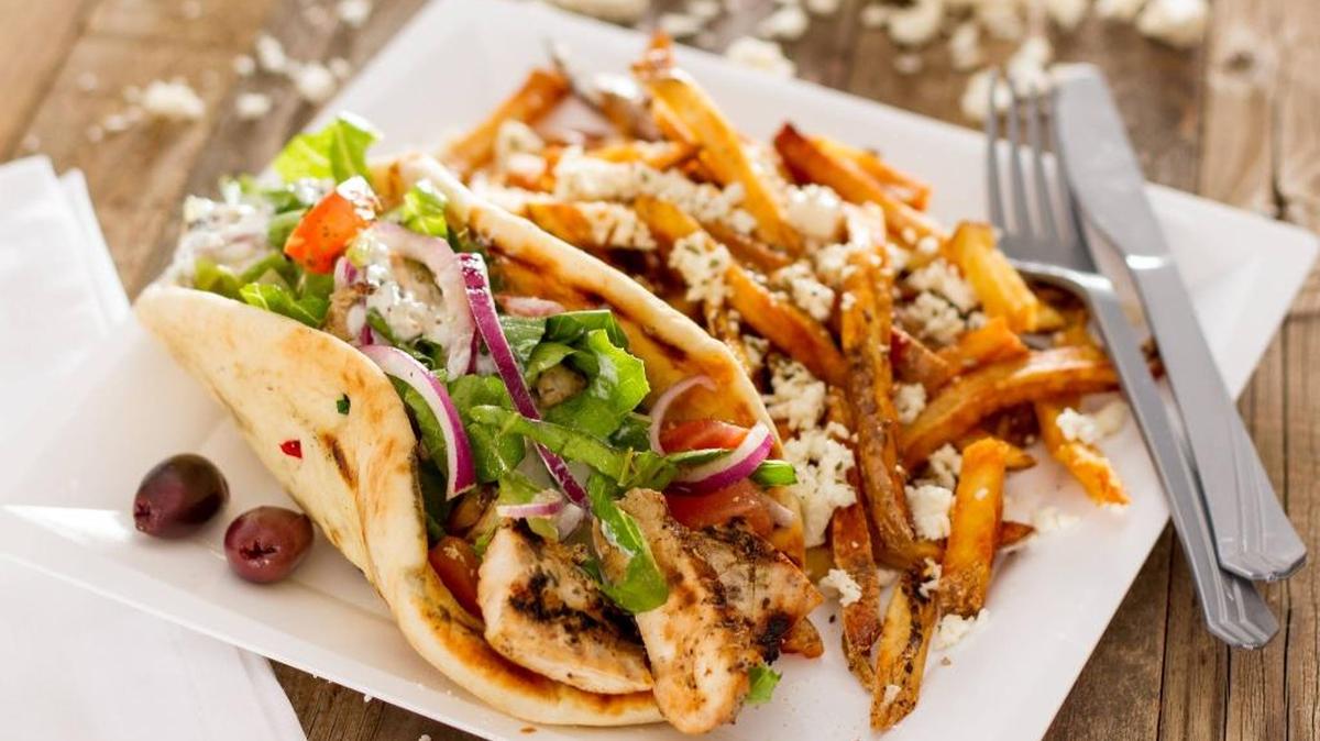 A chicken pita with fries topped with feta cheese and other spices and flavors is on the menu of The Simple Greek. --