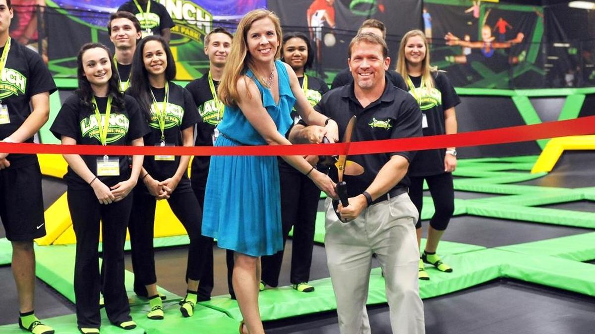 Franchise owners Jessica and Jimmy Fullerton hold the scissors on the main trampoline court to cut the ribbon Thursday for the opening of Launch Trampoline Park. The public grand opening is Saturday.