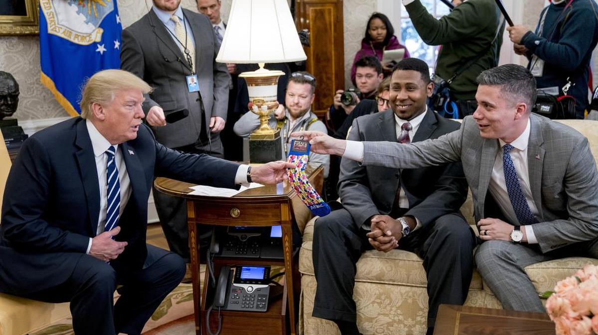 President Donald Trump is handed a pair of Aflac duck socks by Aflac employee Michael Porter of Columbus, Ga., right, during a meeting with American workers on the impact of the tax reform bill in the Oval Office at the White House on Wednesday in Washington. Seated between the president and Porter is Will Harmon, an employee from Columbus-based TSYS. --