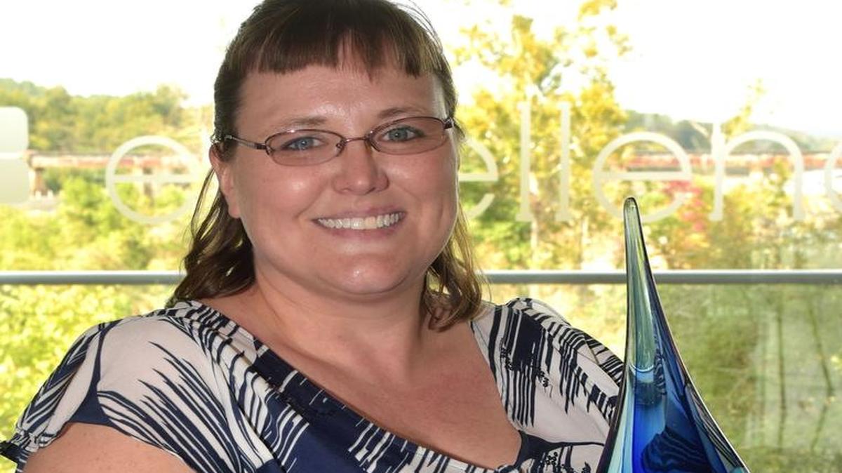 Sara Banks stands with the Phil Tomlinson Heart of TSYS Award that was presented to her earlier this month at the corporate headquarters in downtown Columbus by TSYS Chairman and CEO Troy Woods. Banks, who works at the company’s north center off Moon Road, has been with TSYS 14 years and is currently a business system specialist on a team looking to develop new products and services for clients.