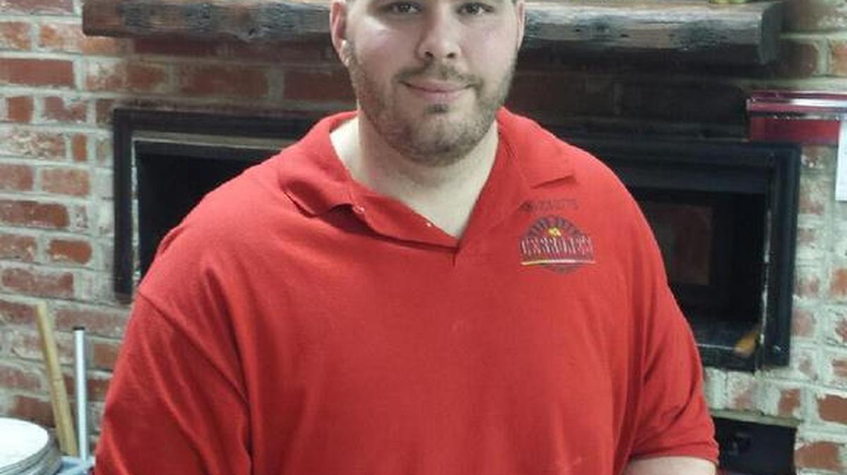 Leo Dicesaris, pizza maker with family-owned Cerrone’s Brick Oven Pizzeria, in north Columbus, holds a just-baked calzone prepared for a customer.