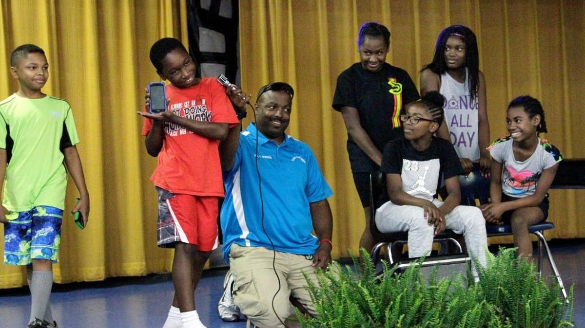 Columbus Police Cpl. Travis Spencer, center, holds the microphone for his D.A.R.E. students during their skit for parents and public safety officers earlier this summer. About 70 boys and girls attended the month-long D.A.R.E. to Be Great summer camp in June, held at Fort Middle School. The camp is one of several grant recipients from the Office of Crime Prevention.