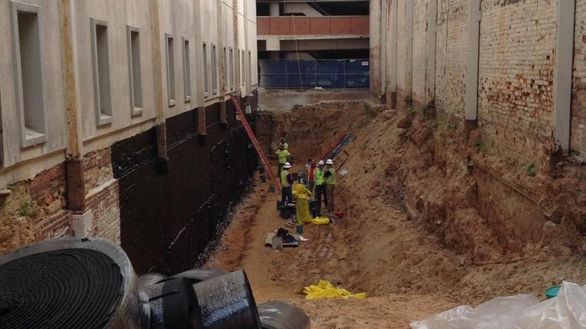 Workers put a protective coating on the Jordan Building basement exterior last month.