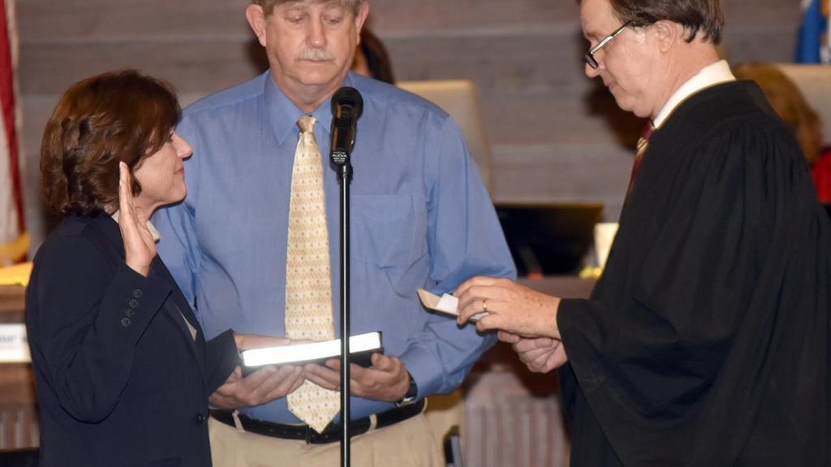 Sheriff Donna Tompkins, with her husband Greg holding the Bible, is sworn in by Superior Court Judge Gil McBride on Tuesday.