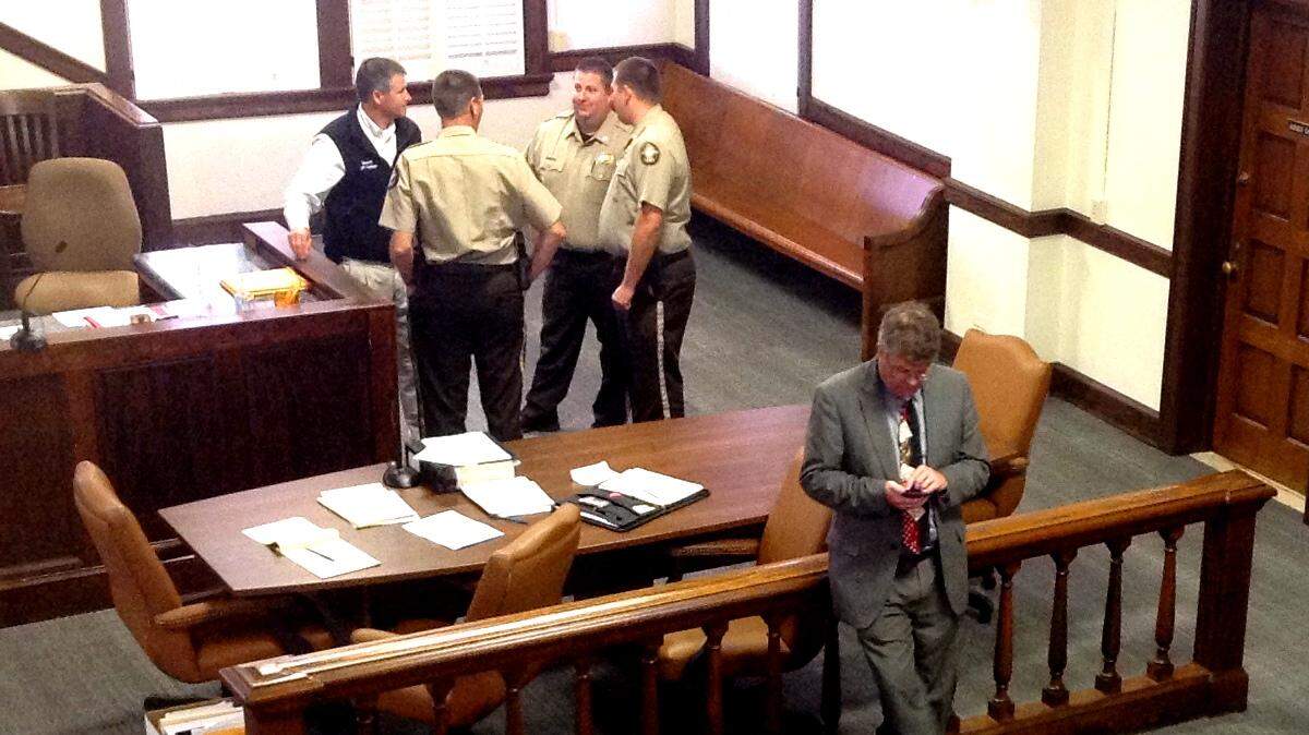 Diana Franklin on the front row talks to friends as defense attorney Kevin Bradley checks his phone behind her.