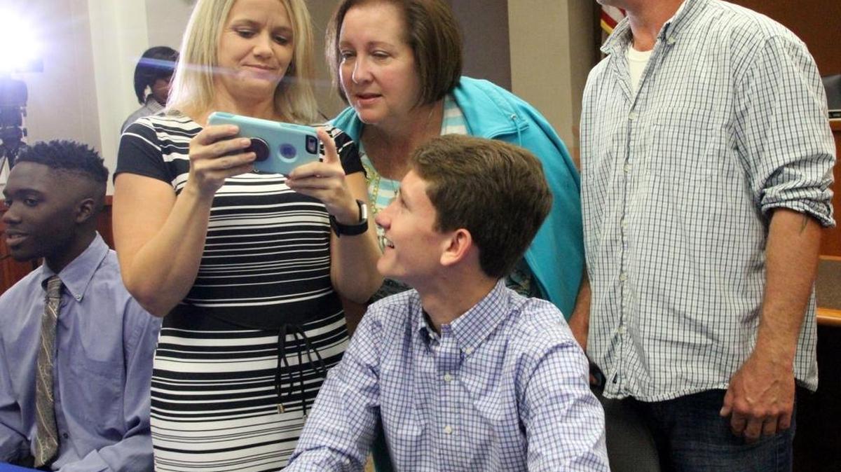 Midland Middle School eighth-grader Evan Stancombe, seated, and his family take pictures after signing his contract as a REACH Georgia Scholarship Program recipient during Wednesday’s ceremony in the Muscogee County Public Education Center. The program, started by Gov. Nathan Deal in 2012, awards high-achieving students from low-income families $10,000 in college financial assistance over four years, plus mentoring and academic help during high school, if they continue to meet the program’s requirements.