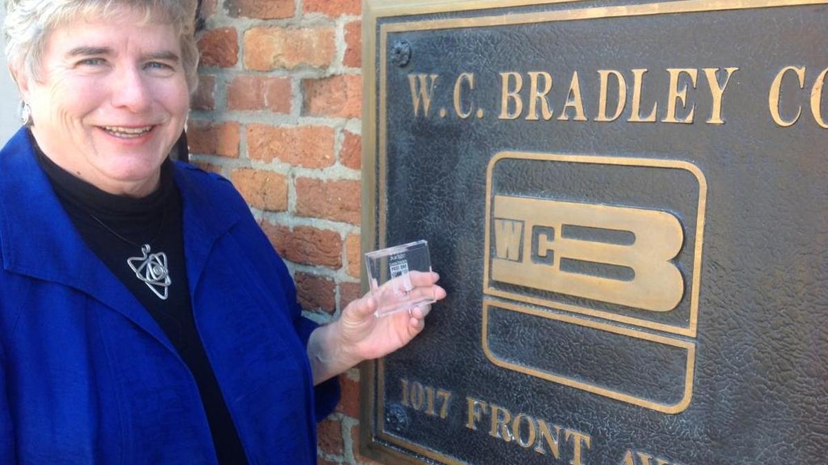 W.C. Bradley Co. vice president for stakeholder relations Susan Wiggins poses April 26, 2017, outside her downtown Columbus office with one of the mementos she has received from the Ledger Enquirer during her 27 years as a Page One Awards judge.