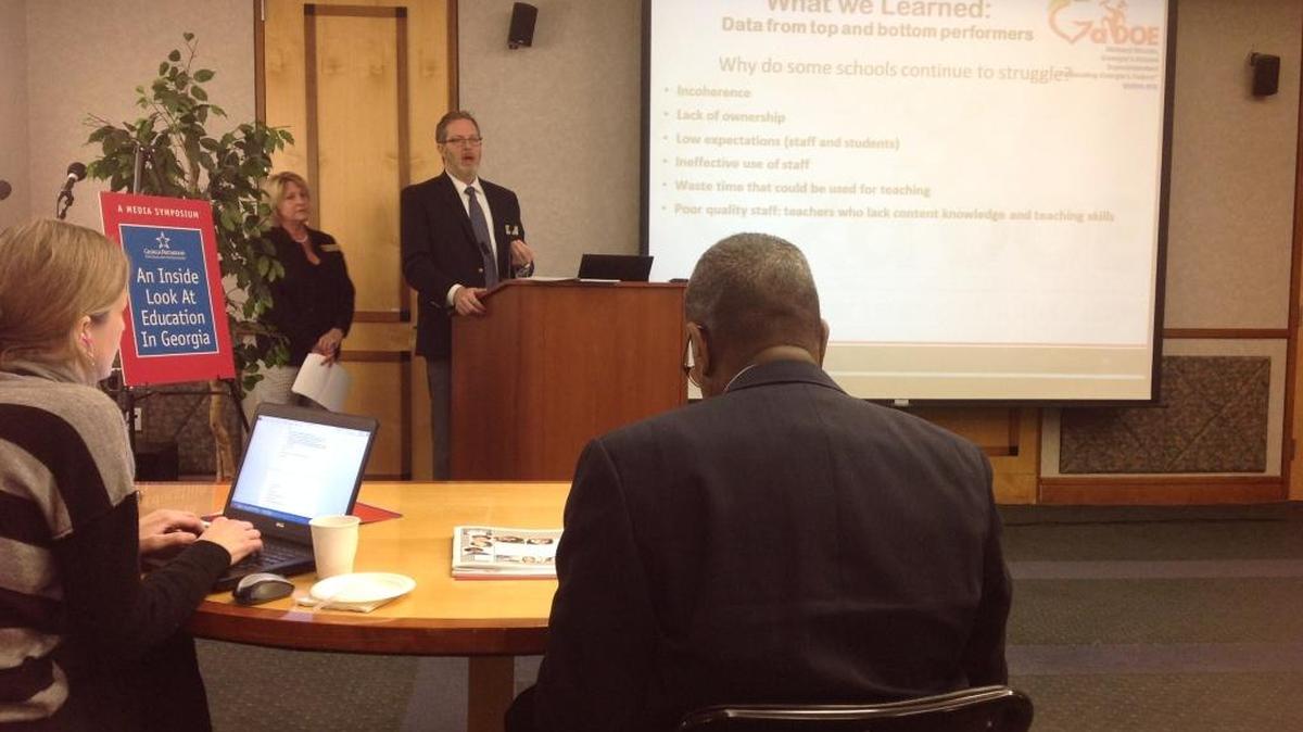 Will Rumbaugh, the Georgia Department of Education’s director of school and district effectiveness, speaks during the Georgia Partnership for Excellence in Education symposium Jan. 6 at the Georgia Public Broadcasting headquarters in Atlanta. Avis King, the GaDOE’s deputy superintendent for school improvement, stands next to Rumbaugh.