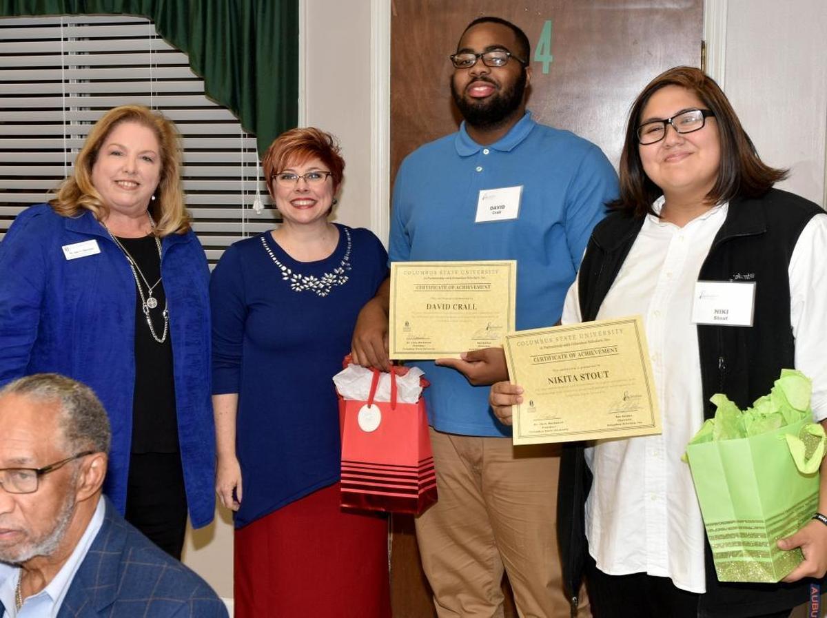 From left, Jan Burcham, associate dean of Columbus State University’s College of Education, and Bridget Markwood, the CEO of the Leader NU and wife of CSU president Chris Markwood, present certificates of achievement to Columbus Scholars David Crall and Niki Stout during the Columbus Scholars holiday banquet Monday, December 4, 2017, at Fourth Street Missionary Baptist Church.