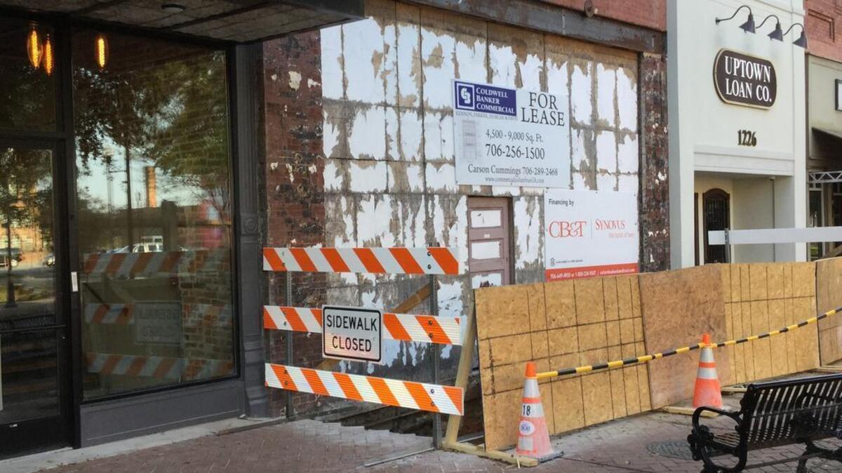 A portion of the 1200 Broadway sidewalk on the east side is blocked as workers install footings for a new balcony.