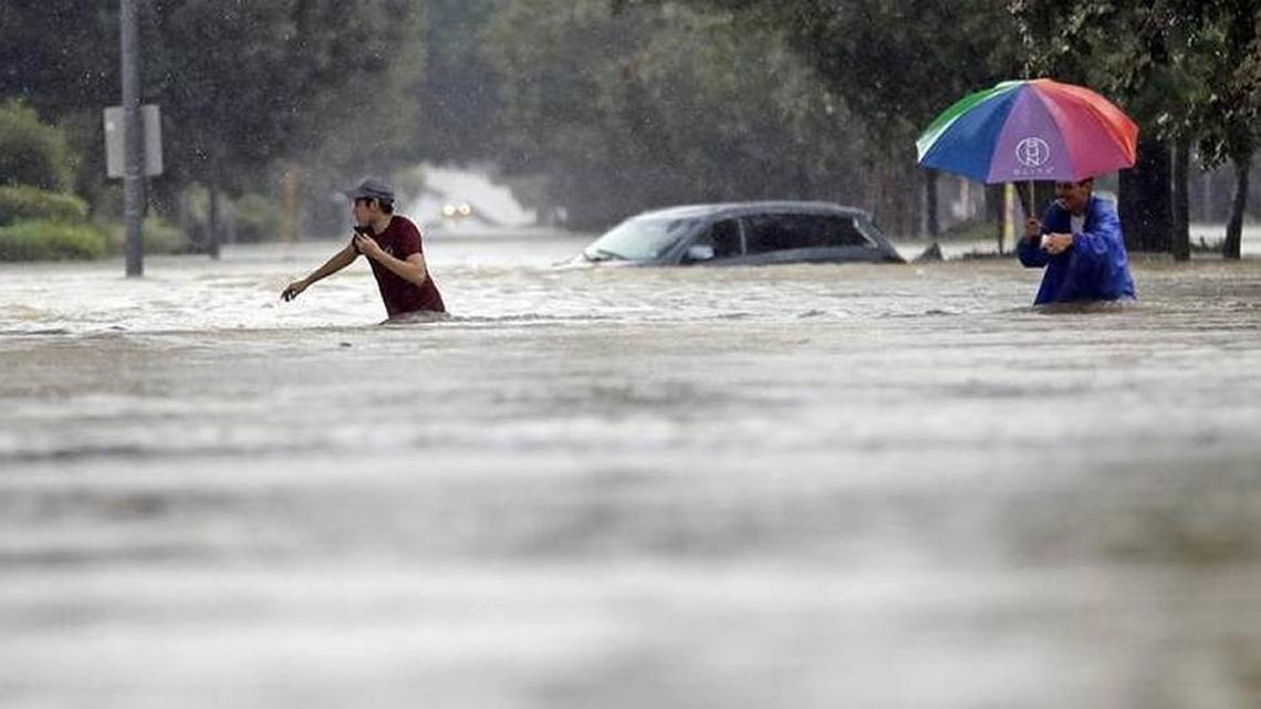Moses Juarez, left, and Anselmo Padilla wade through flooding Sunday, Aug. 27, 2017, in Houston, Texas.