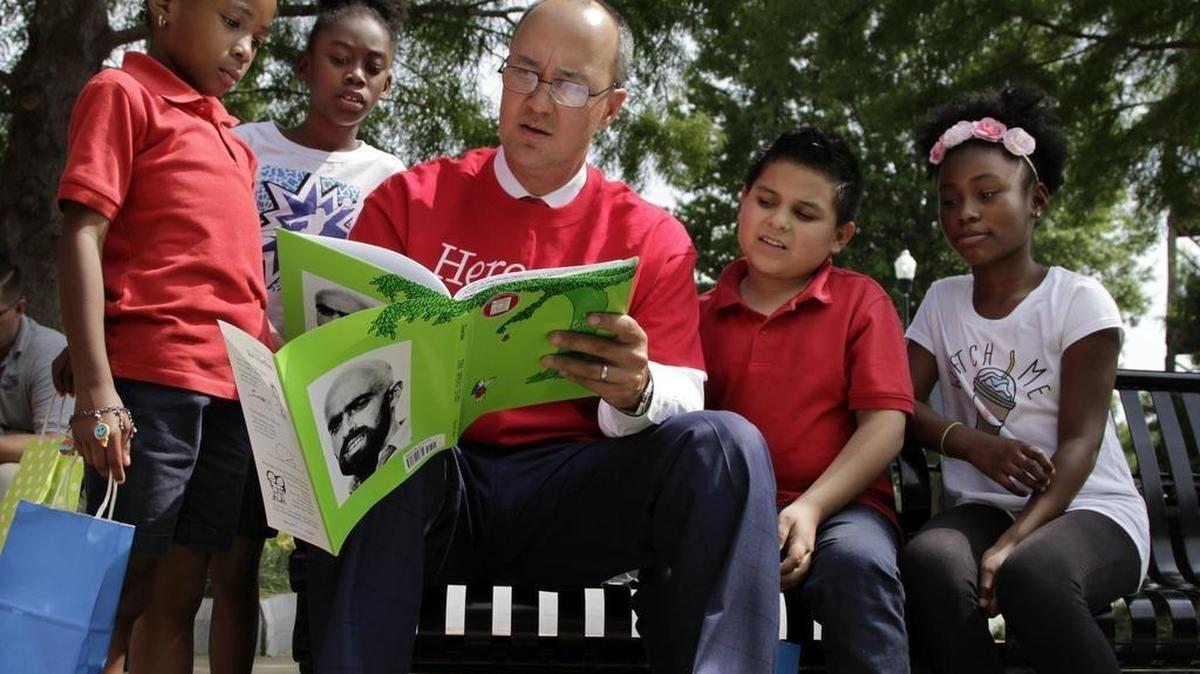 Gene Perkins, the Synovus Senior Director of Private Wealth, reads "The Giving Tree" by Shel Silverstein with a group of Boys & Girls Club youngsters Thursday during a book giveaway on the Synovus Centre lawn. The event capped off a book drive that netted 1,700 books for the clubs' libraries.