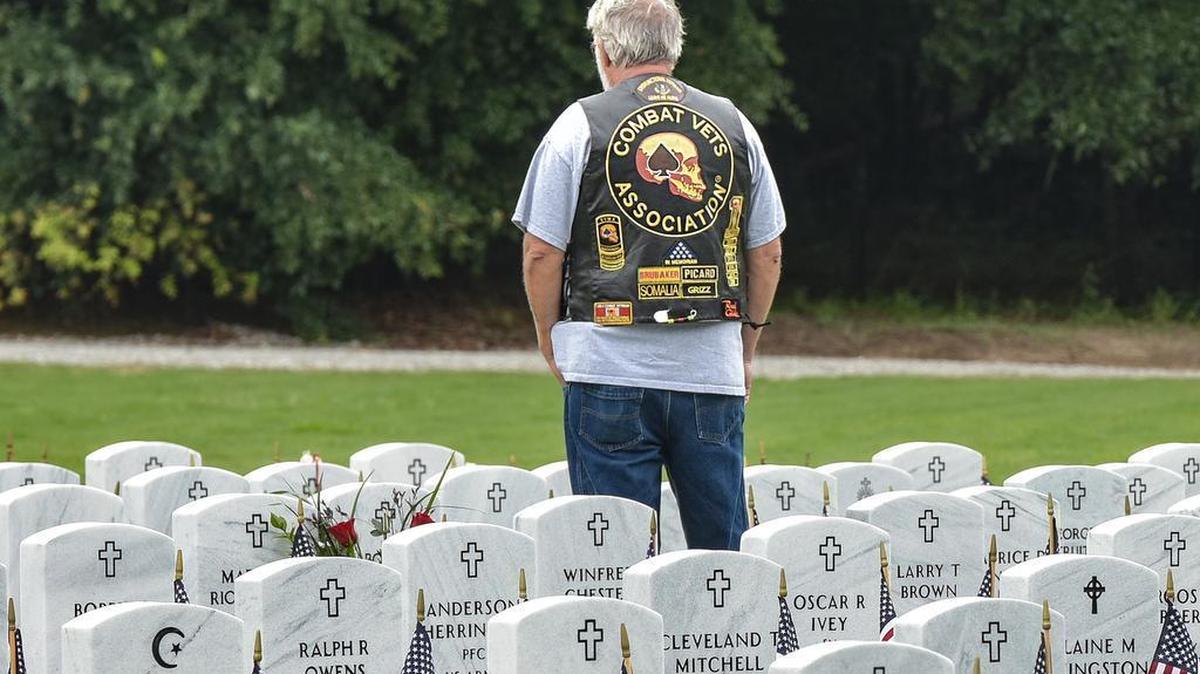 Veteran Terry Sandefur paying respect to veterans interred at Fort Mitchell National Cemetery during the annual Memorial Day program Sunday, May 27, 2018.