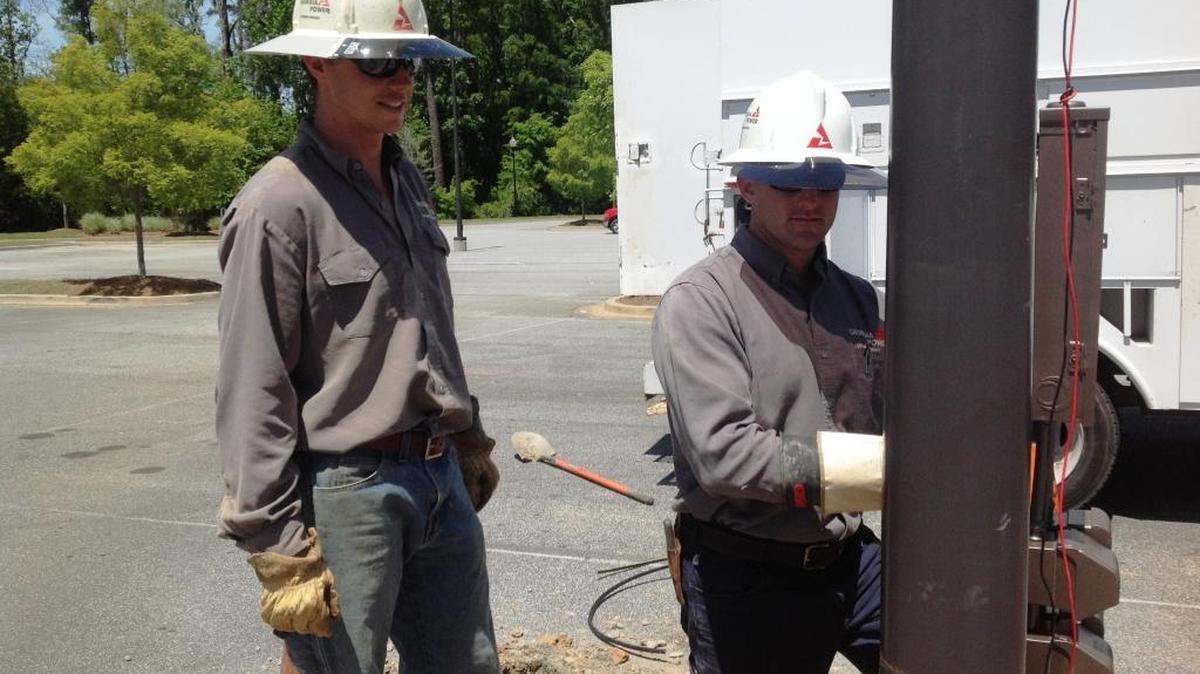 Georgia Power linemen Ricky Mount, left, and Aaron Bush install electrical service in the parking lot of the National Infantry Museum.