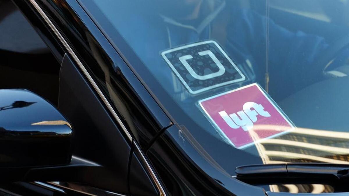 In this Tuesday, Jan. 12, 2016, file photo, a driver displaying Lyft and Uber stickers on his front windshield drops off a customer in downtown Los Angeles.
