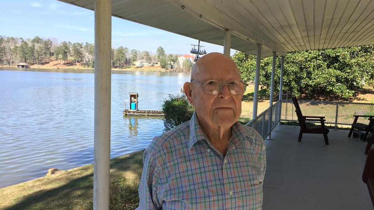 Dewey Reaves stands on the porch of his home on Lake Oliver as he discussed his 100th birthday on March 16, 2018.