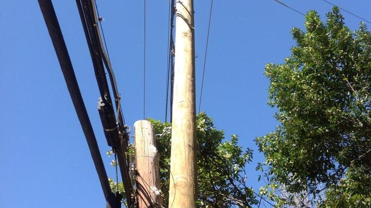 A four-foot section of an old broken utility pole hangs suspended from power lines on Steam Mill Road.