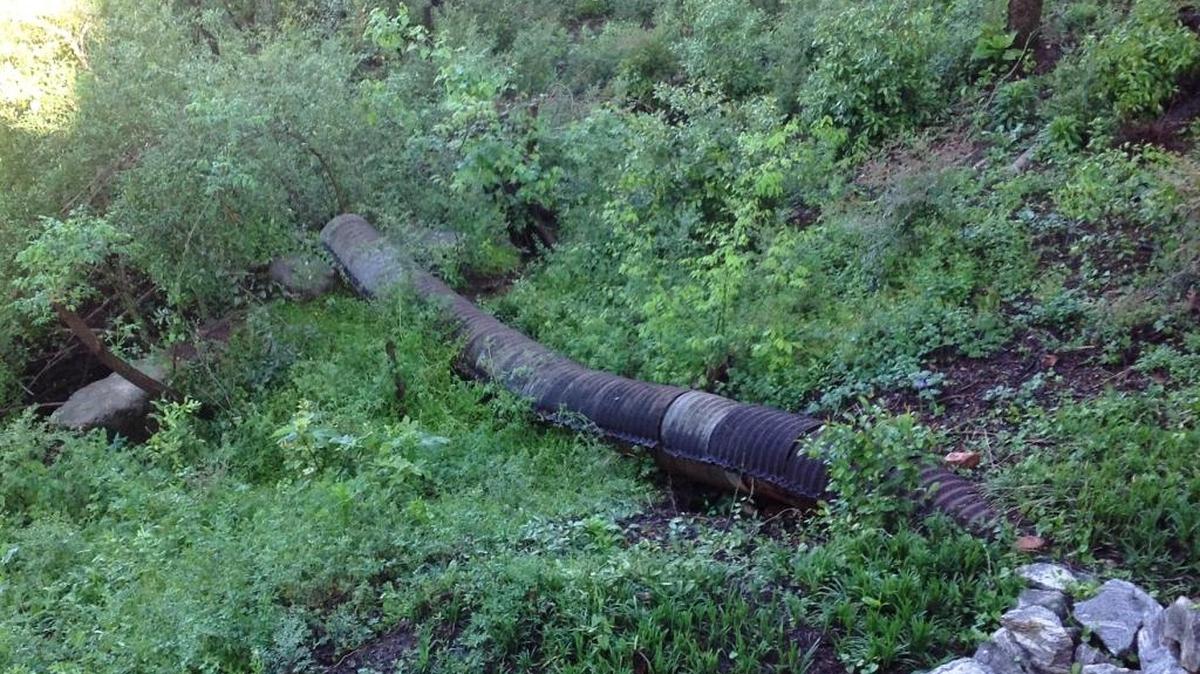 A large metal drainpipe that runs under Lisa’s house drains water down the hill toward the RiverWalk.