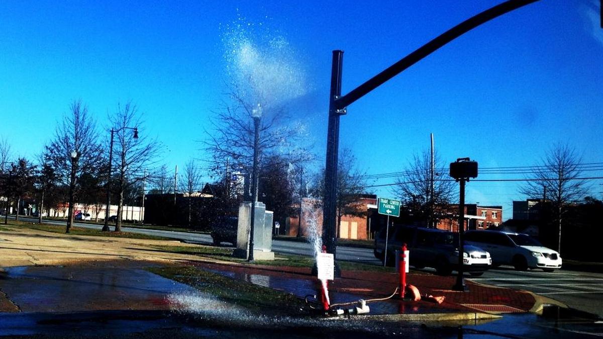 A temporary water line spews Sunday morning at the corner of Veterans Parkway and Eighth Street.