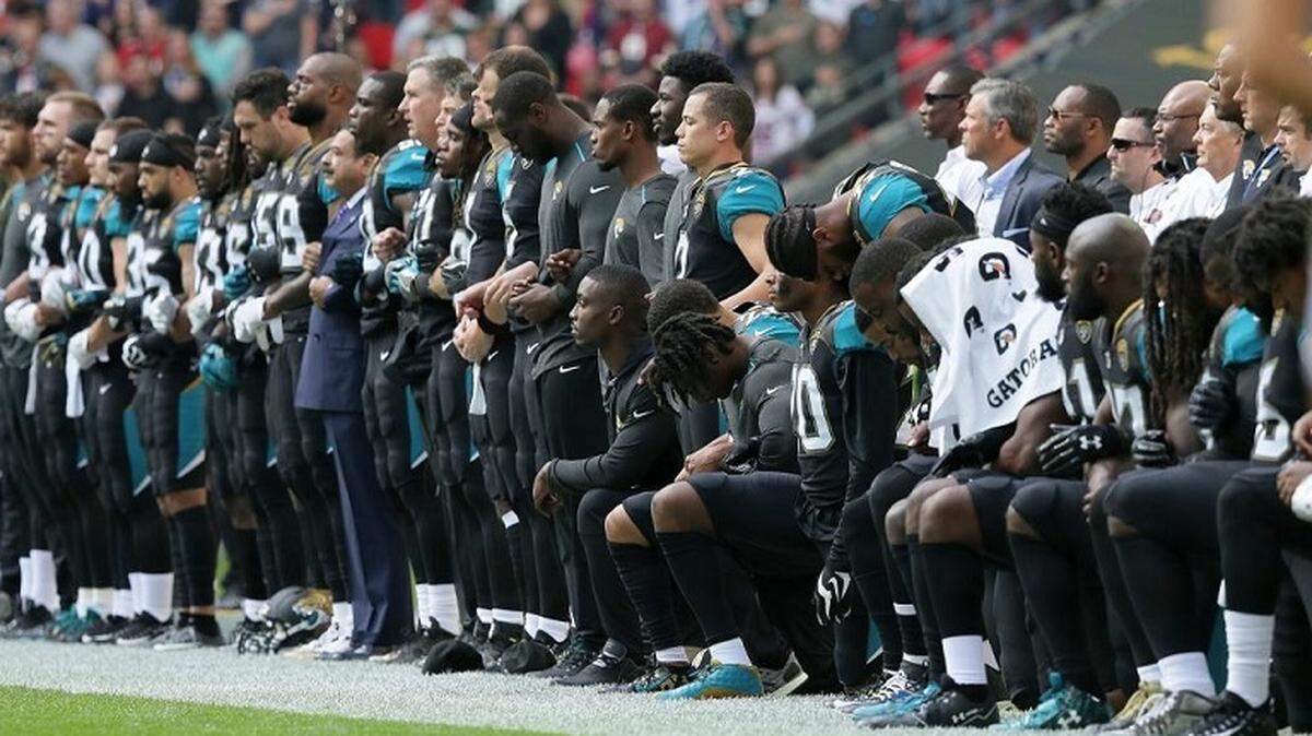 FILE - In this Sept. 24 photo, some Jacksonville players stand and some kneel during the playing of the national anthem before their game against Baltimore. Muscogee County School Superintendent David Lewis said by law he cannot prevent high school students from kneeling during the anthem “despite my personal feelings.”