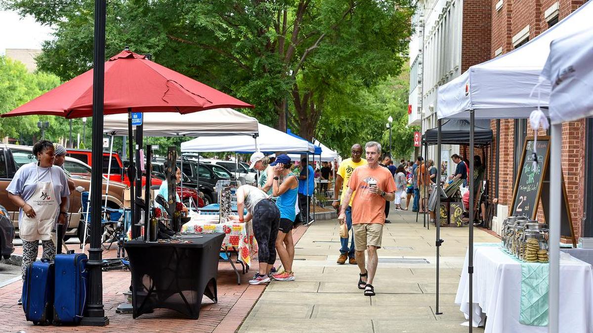 Pedestrians walk along Broadway visiting the various vendor booths during Saturday’s Uptown Columbus Market Days on Broadway.