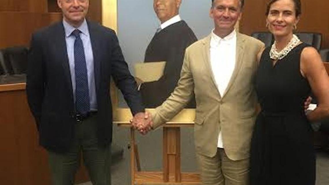 Columbus artist Bo Bartlett, center, and his wife Betsy Eby pose Thursday night with Pulitzer Prize winning writer Ian Urbina of the New York Times beside Bartlett’s portrait of former U.S. District Court Judge Ricardo Urbina.