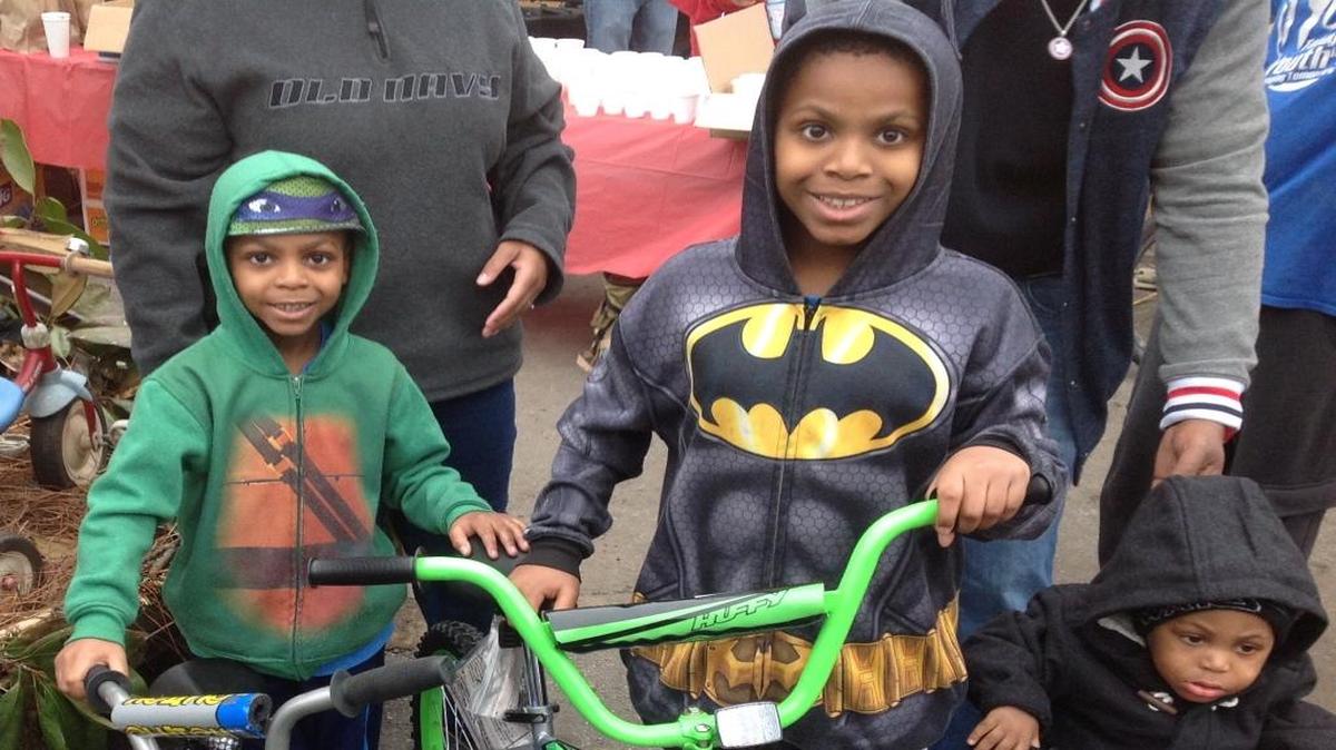 King Johnson, 5, Camar Johnson, 8, and 1-year-old Ty Johnson beam as they receive the first three of 995 bicycles being given away Saturday.