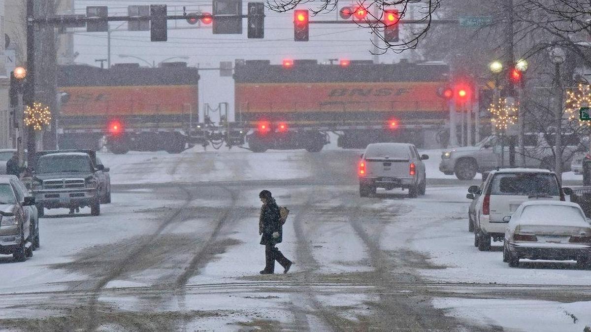 A pedestrian crosses a snow covered street in downtown Bismarck, N.D., on Monday, Dec. 4, 2017. Blizzard warnings were posted for northwest Minnesota, southeast North Dakota and northeast South Dakota where winds were expected to whip up snow and create white-out conditions.