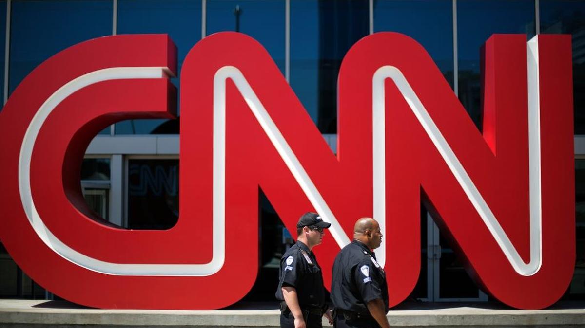 FILE - In this Aug. 26, 2014 file photo, security guards walk past the entrance to CNN headquarters in Atlanta. (AP Photo/David Goldman, File)