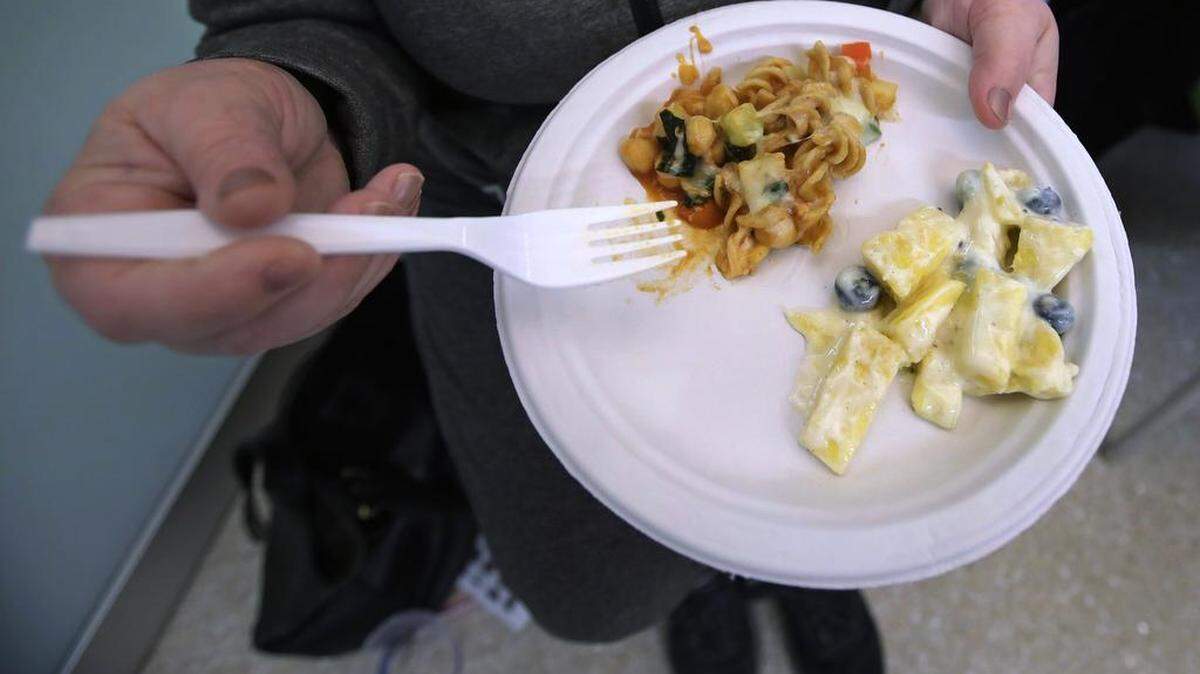 The plate features whole grain pasta with fresh vegetables as a main course, with pineapple, blueberries and yogurt as a dessert.