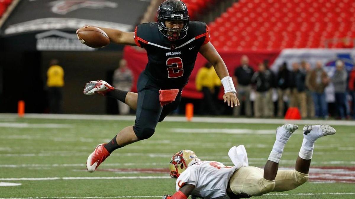 Macon County quarterback K'hari Lane eludes the tackle of McIntosh County Academy defender Daiquon Drake in the first half of the Class A public state championship high school football game Dec. 10. at the Georgia Dome in Atlanta. Macon County won 35-0.
