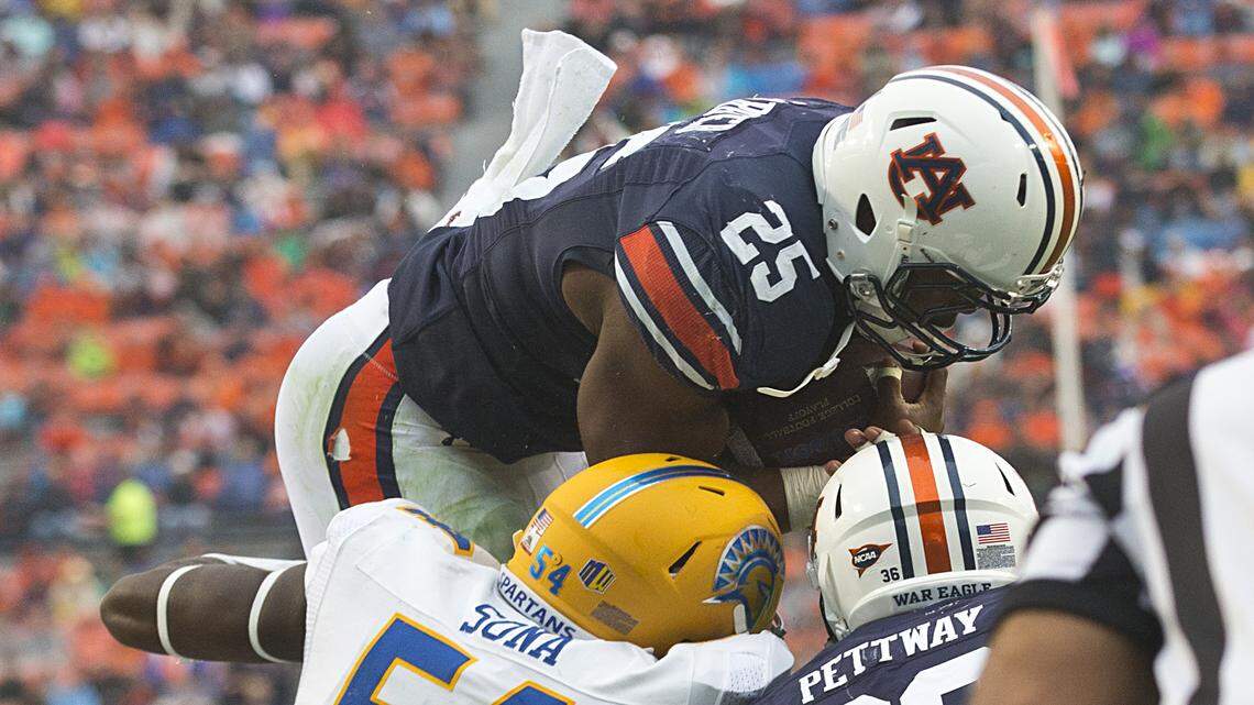 Auburn running back Peyton Barber (25) leaps over San Jose State linebacker Epie Sona (54) to score a touchdown during the second half of an NCAA college football game, Saturday, Oct. 3, 2015, in Auburn, Ala. Auburn won 35-21. (AP Photo/Brynn Anderson)