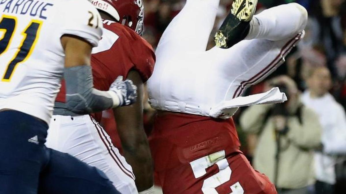 Alabama quarterback Jalen Hurts lands after diving over a tackler during Saturday night’s game.