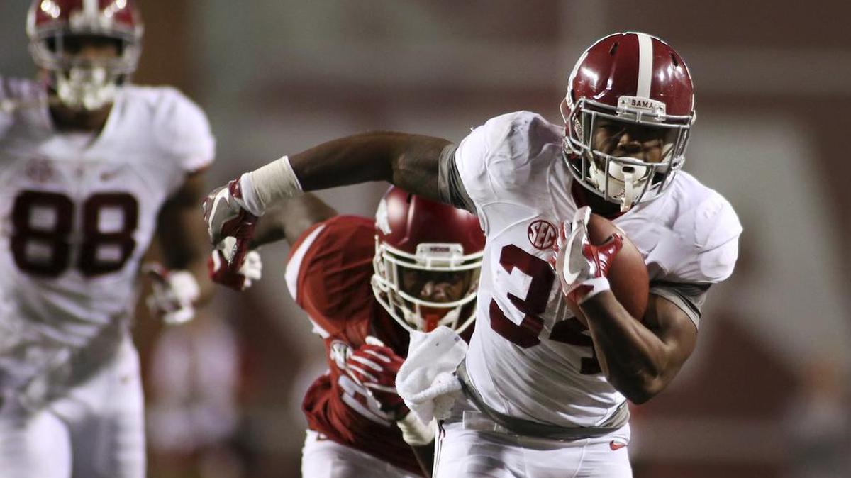 Alabama’s Damien Harris runs away from an Arkansas defender during the second quarter of an NCAA college football game Saturday.