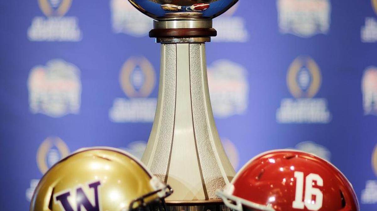 The trophy for the Peach Bowl NCAA college football game stands beside helmets from Washington, left, and Alabama ahead of tomorrow's NCAA college football game in Atlanta, Friday, Dec. 30, 2016.