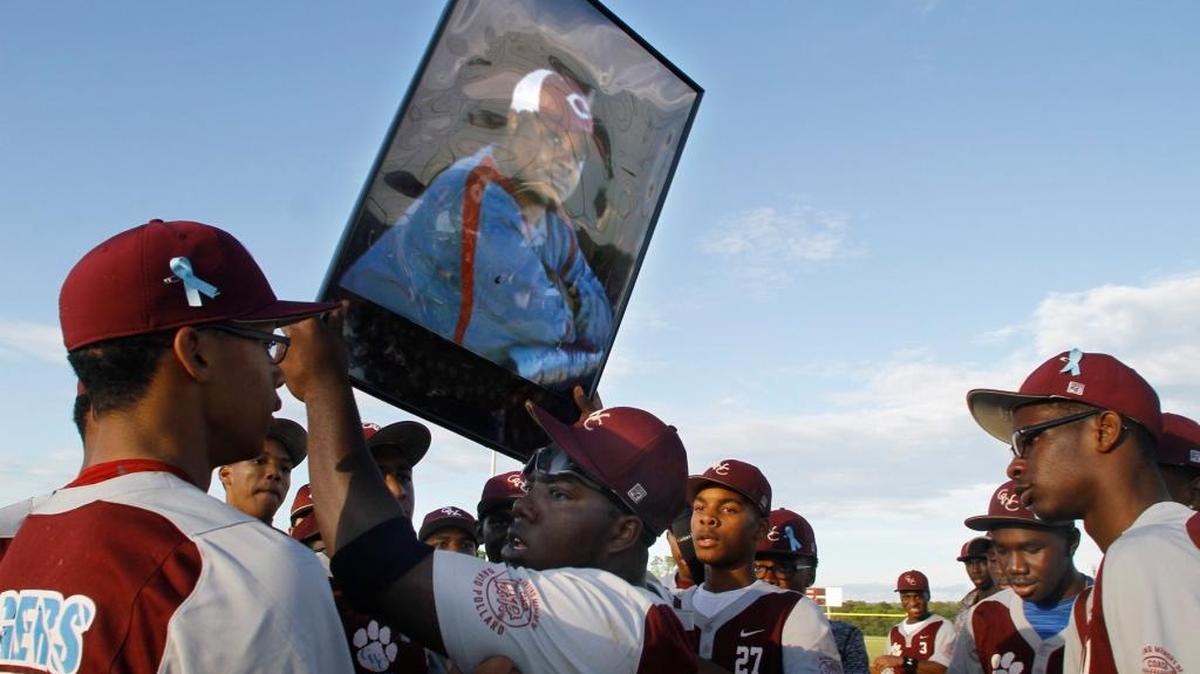 Carver High teammates hold high a photograph of their head coach David Pollard following their 5-3 win over Shaw High Friday, April 21, for their first Region 1-5A win in two years. Pollard was killed in a traffic accident April 18 just blocks from the school.
