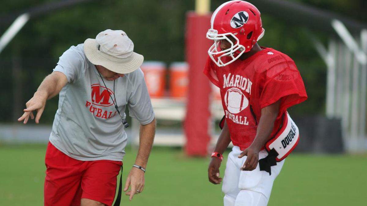 Coach Mike Swaney and quarterback Quentez Battle discuss his mechanics during practice Sept. 8 at Marion County.