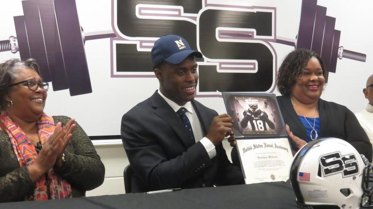 Smiths Station’s Deondrae Williams celebrates his signing with the Naval Academy while grandmother Joanne Williams and mother Tawanna Williams cheer him on