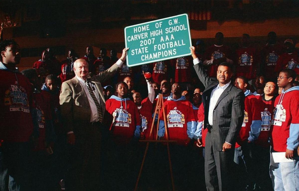 Then Columbus Mayor Jim Wetherington, left, and City Manager Isaiah Hugley unveil a road sign proclaiming Carver’s championship season.