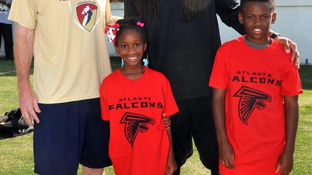 Former Atlanta Falcons LB Buddy Curry and current Atlanta Falcons LB Philip Wheeler pose for a picture Wednesday with Jaelynn Gaskings and Tyquis Brown during the Atlanta Falcons Youth Football Clinic at Memorial Stadium.