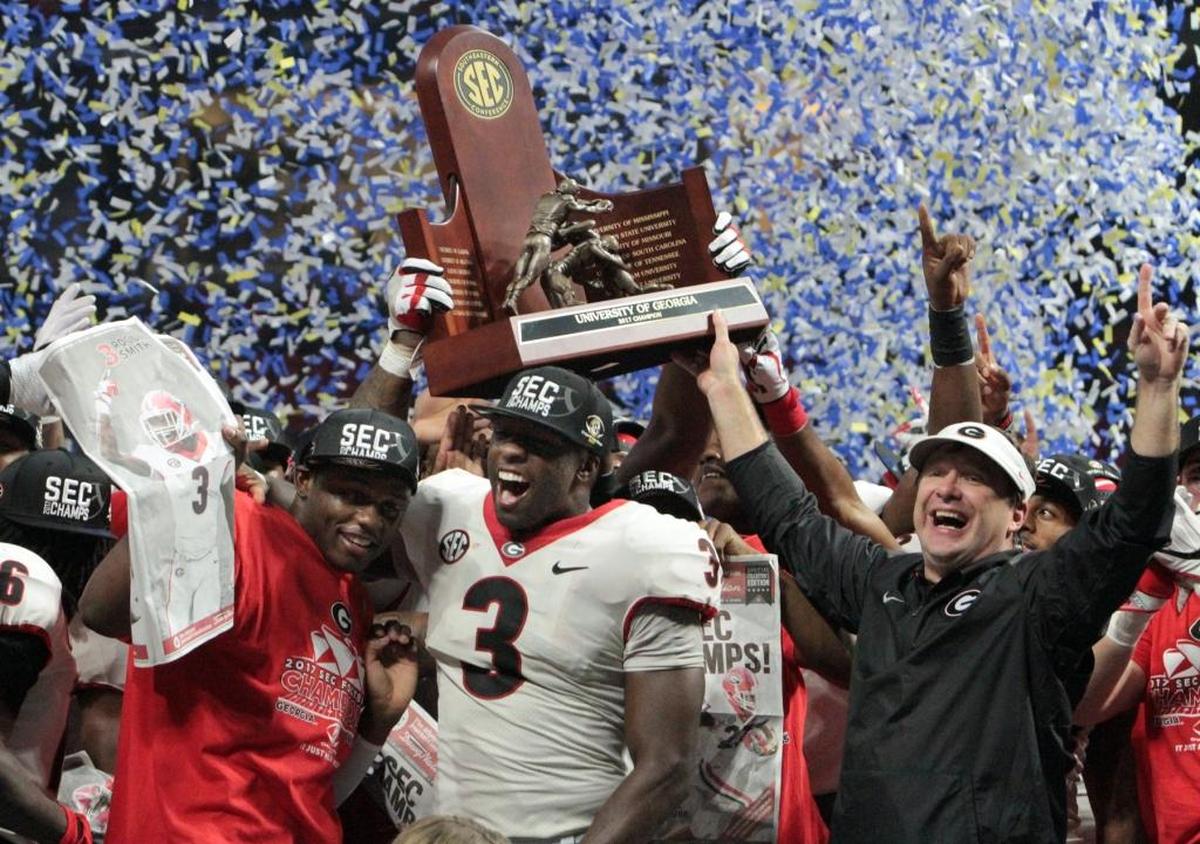 University of Georgia's Roquan Smith, center, and head coach Kirby Smith celebrate with the SEC Championship trophy after the Bulldogs beat Auburn 28-7 at Mercedes-Benz Stadium in Atlanta. Smith was named the game's MVP.