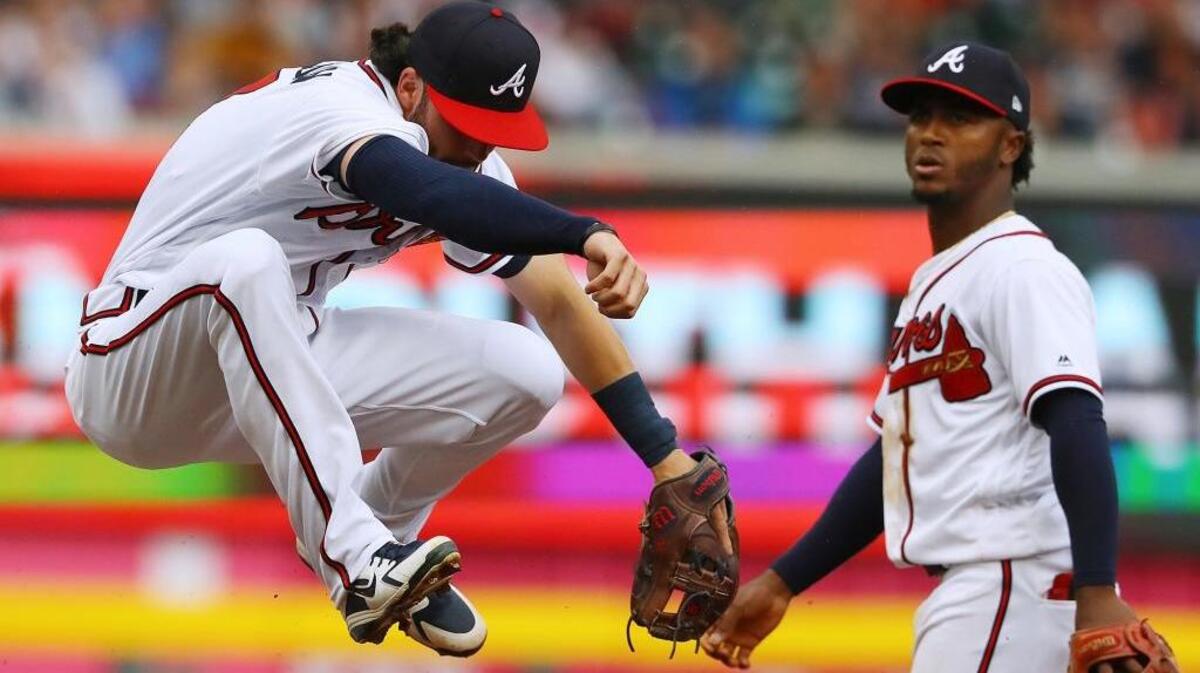 Atlanta Braves second baseman Ozzie Albies looks on while shortstop Dansby Swanson gets some air turning a double play over Philadelphia Phillies' Andrew Knapp during the fifth inning of a baseball game, Thursday, March 29, 2018, in Atlanta.