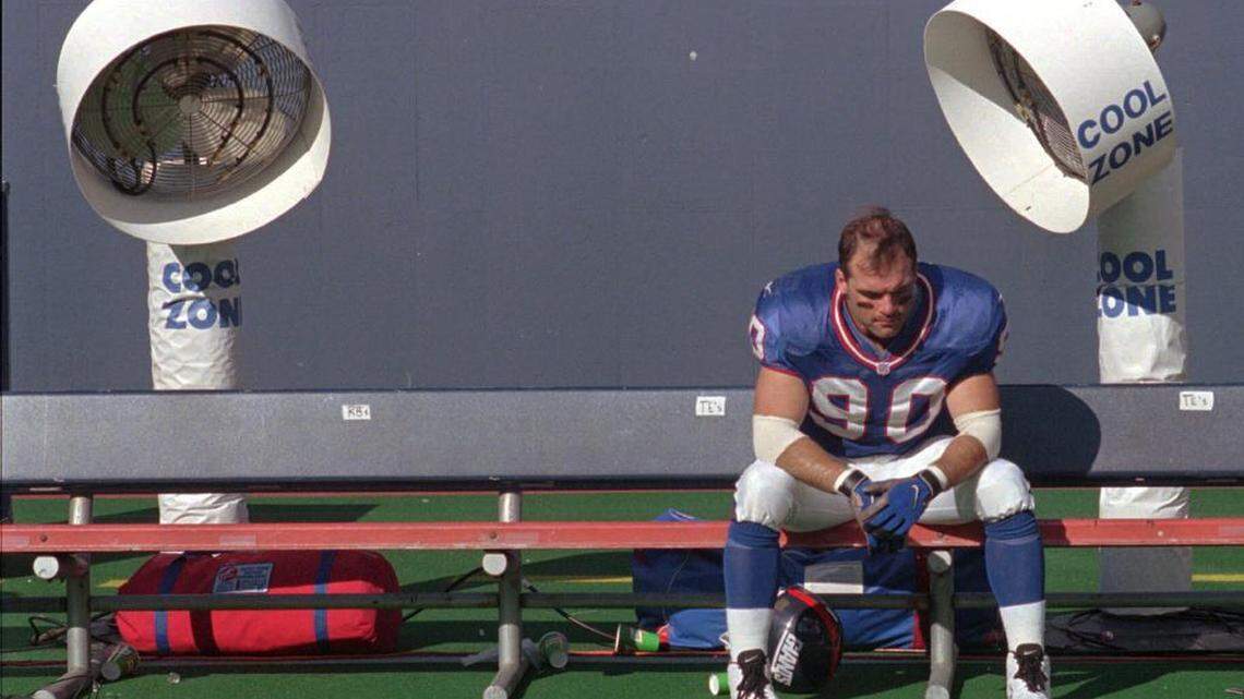 FILE - In this Sept. 14, 1997, file photo, New York Giants linebacker Corey Widmer sits on the team bench in front of two Cool Zone fans after losing to the Baltimore Ravens, 24-23, at Giants Stadium in East Rutherford, N.J. (AP Photo/Norm Sutaria, file)